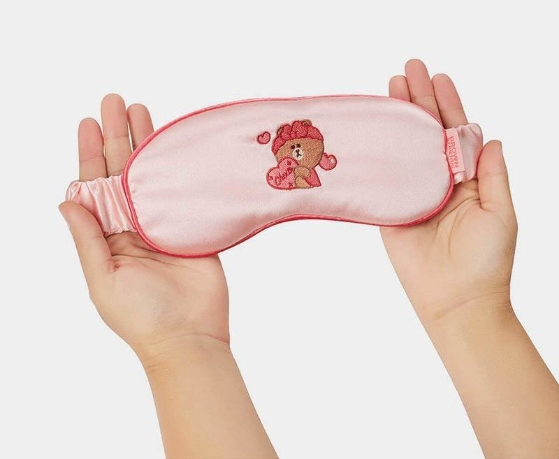 A person holding sleep eye mask in their hands