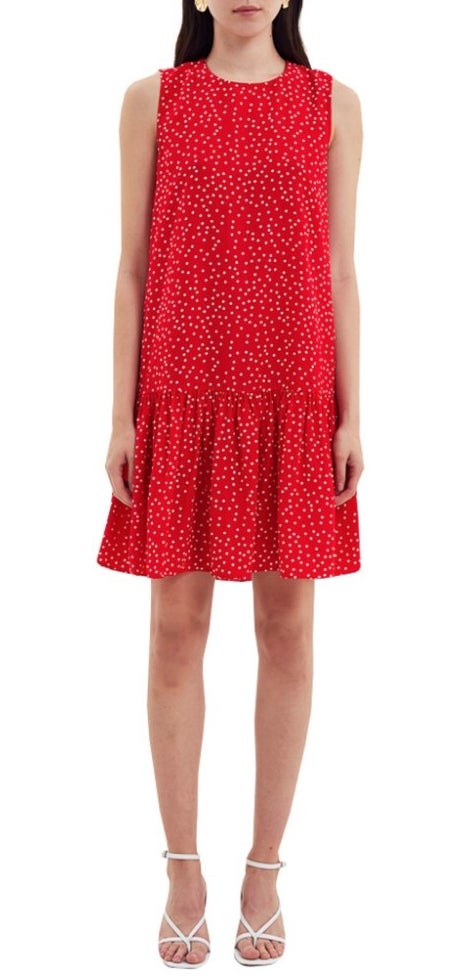 A model wearing a red/white polka dotted, a-line shift dress with a ruffled hem
