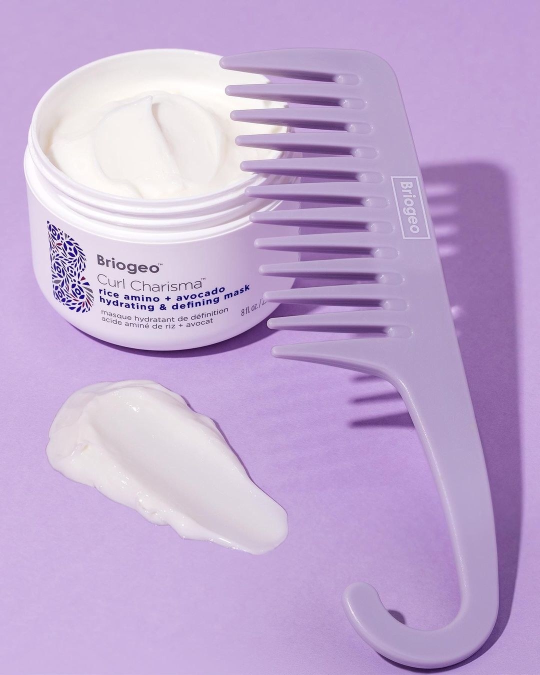 A large wide-tooth comb next to a tub of hair product