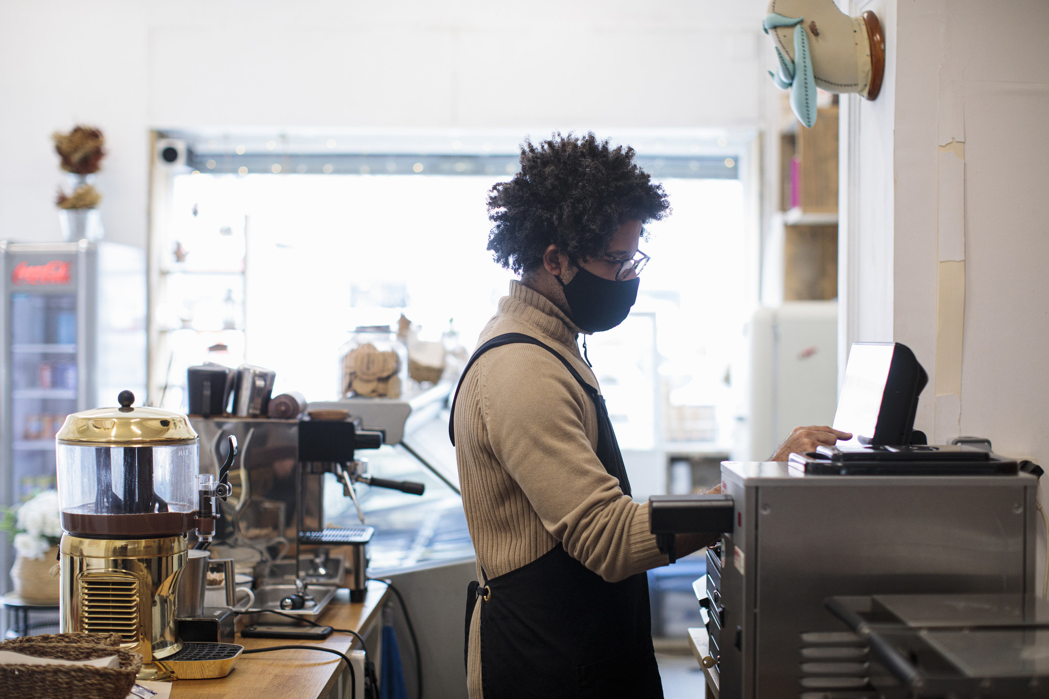 A barista wearing a face mask putting an order in on the computer