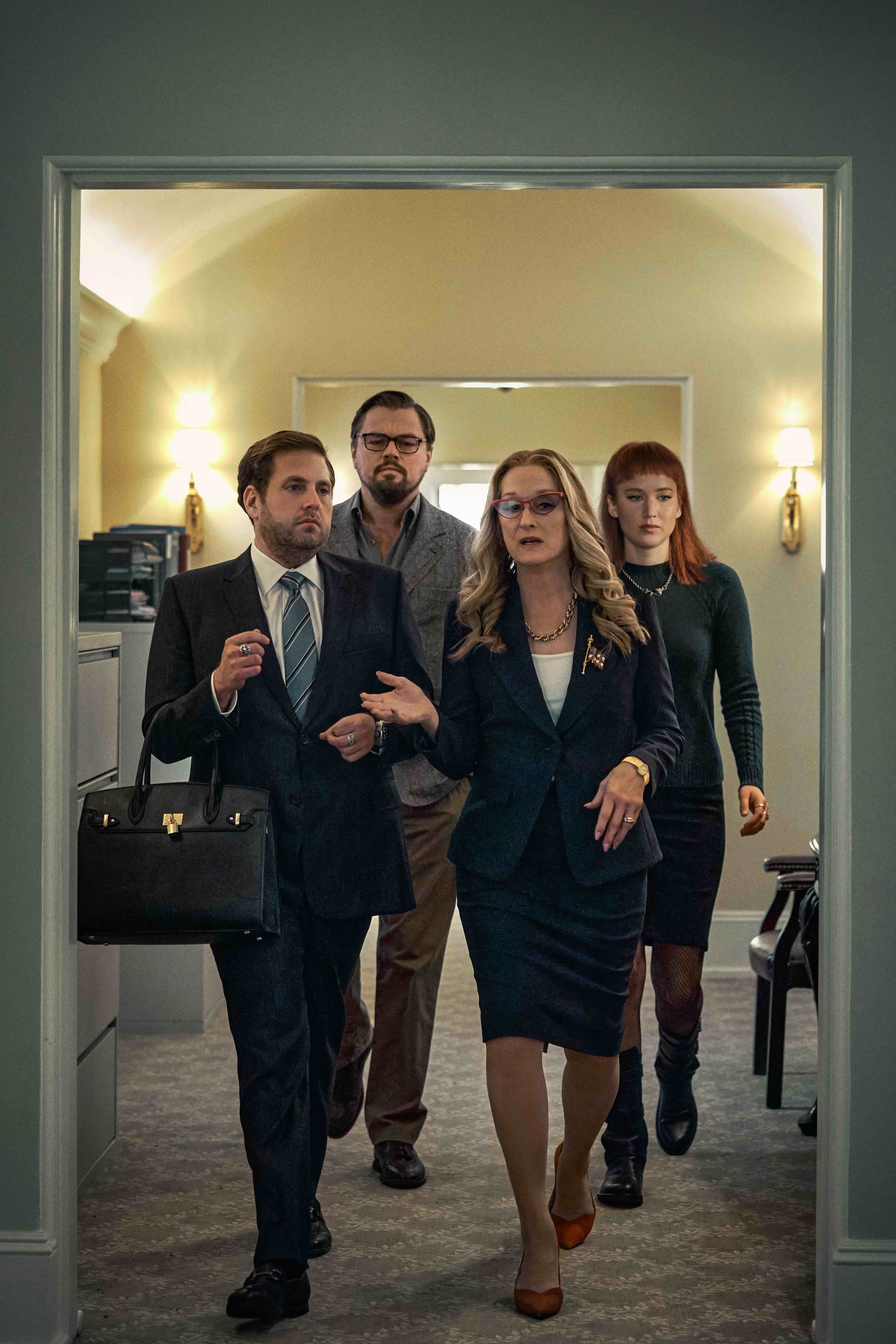 Meryl&#x27;s character walking through a hallway as Jonah, who&#x27;s holding her purse, follows along with Leo and Jennifer