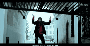 GIF of Abhishek Bachchan throwing an iron gate towards hooded men as Priyanka Chopra ducks down