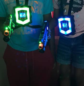Reviewer's photo showing two people wearing the glowing vests and holding lit up laser guns