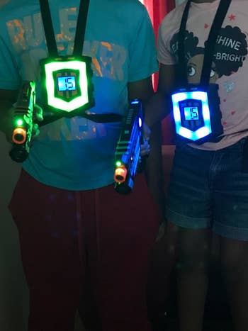 Reviewer's photo showing two people wearing the glowing vests and holding lit up laser guns