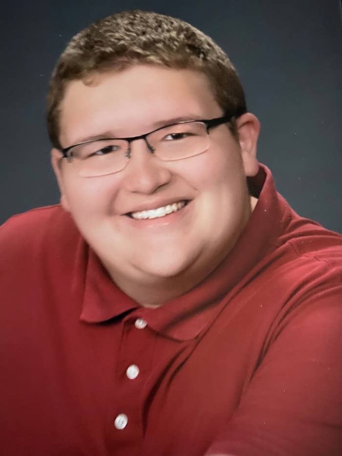 A young man in a red polo shirt smiles at the camera