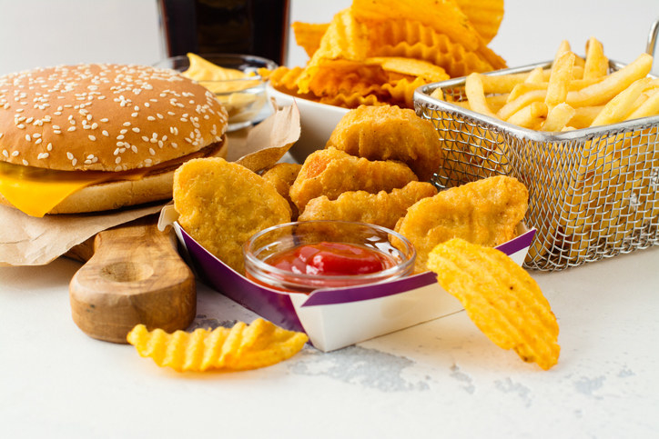 A cheeseburger, chicken nuggets with ketchup, and french fries and potato chips