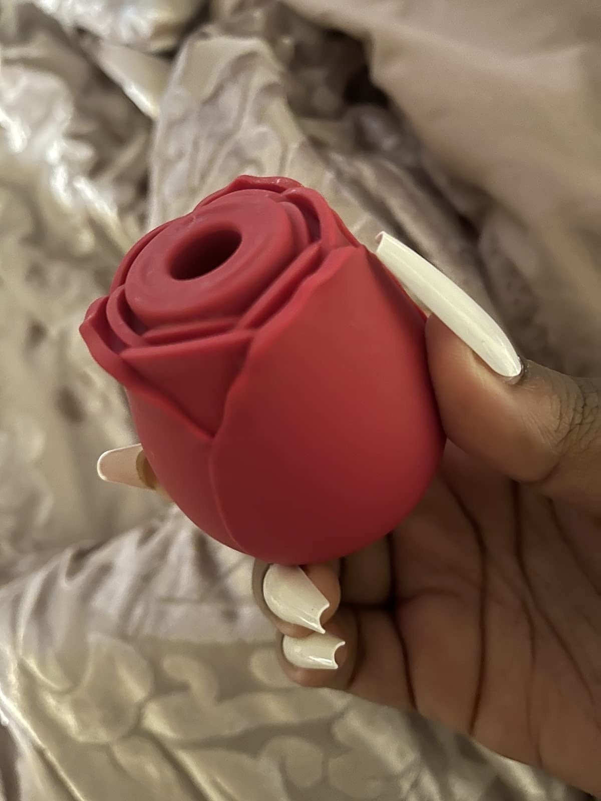 A reviewer holding the flower vibrator with a suction mechanism in the middle and several petals all around