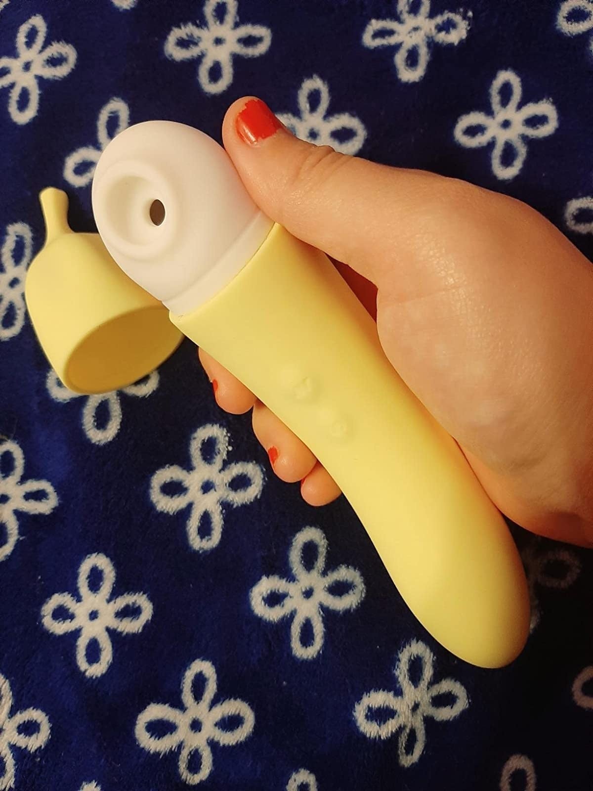 A reviewer holding the banana-shaped toy inside a yellow case with suction on one end and a curve on the other