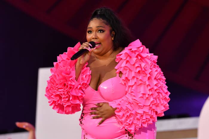Lizzo performs onstage in a pink bodysuit