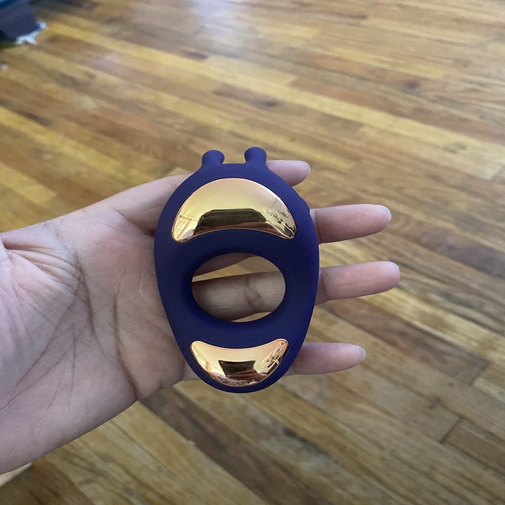 A reviewer holding the vibrating ring, with a circular cutout in the middle and two small probes on the inside