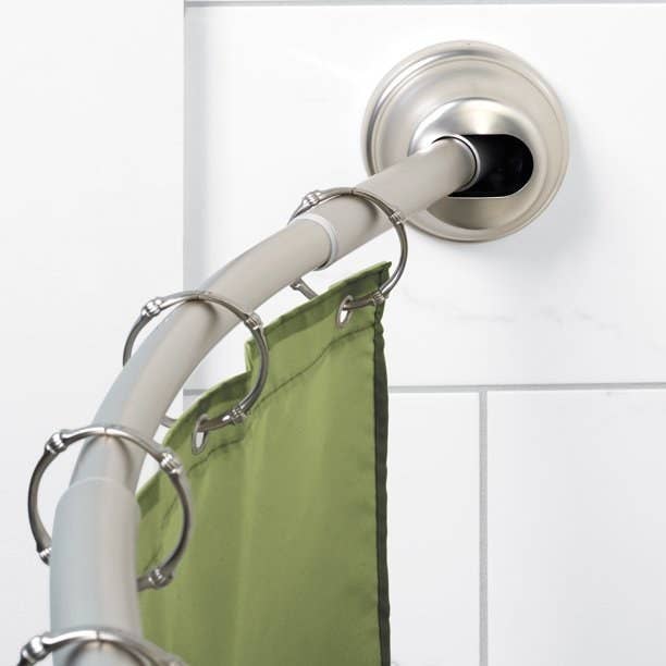 Curved rod holding green shower curtain.