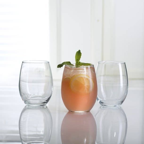 Three stemless glasses shown, two empty, one in the middle filled with a drink.