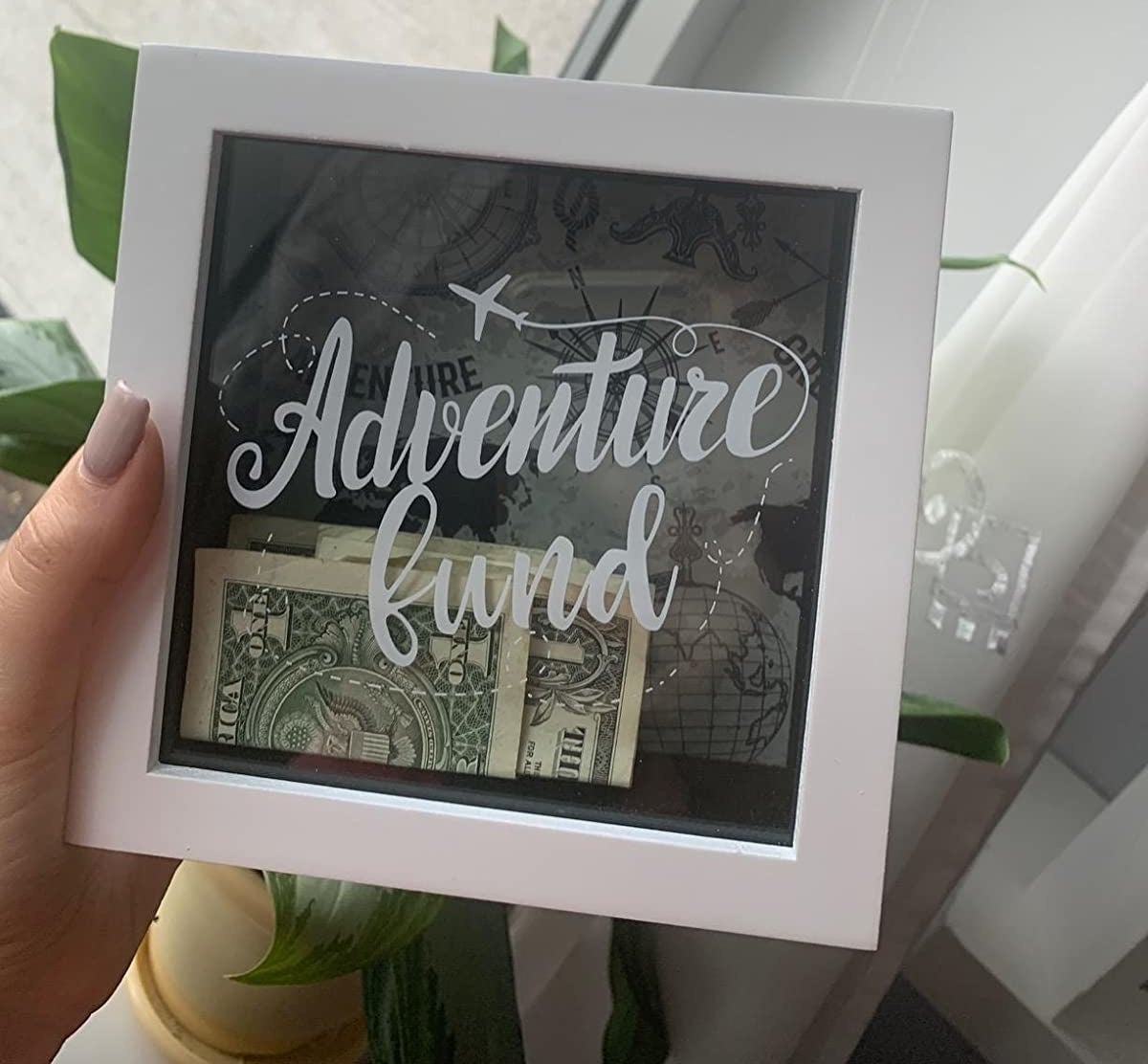 image of reviewer holding up vacation fund box with a few dollars inside