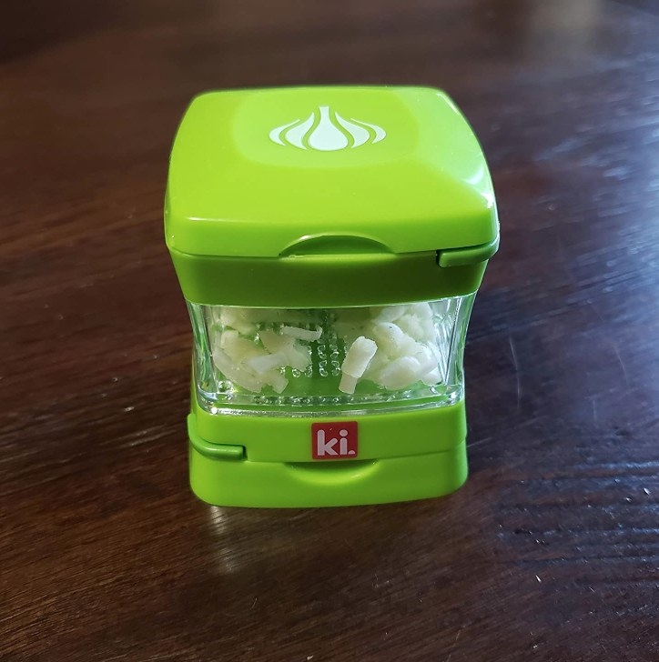 Green garlic chopper with clear storage container with minced garlic inside