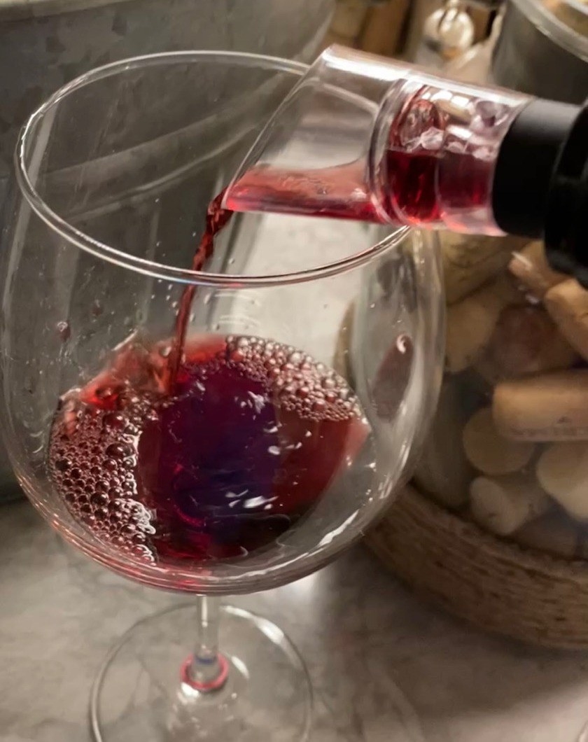 reviewer pours wine through aerator into a wine glass