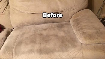 a reviewer photo of a tan couch with a dark stain on the seat and text reading 