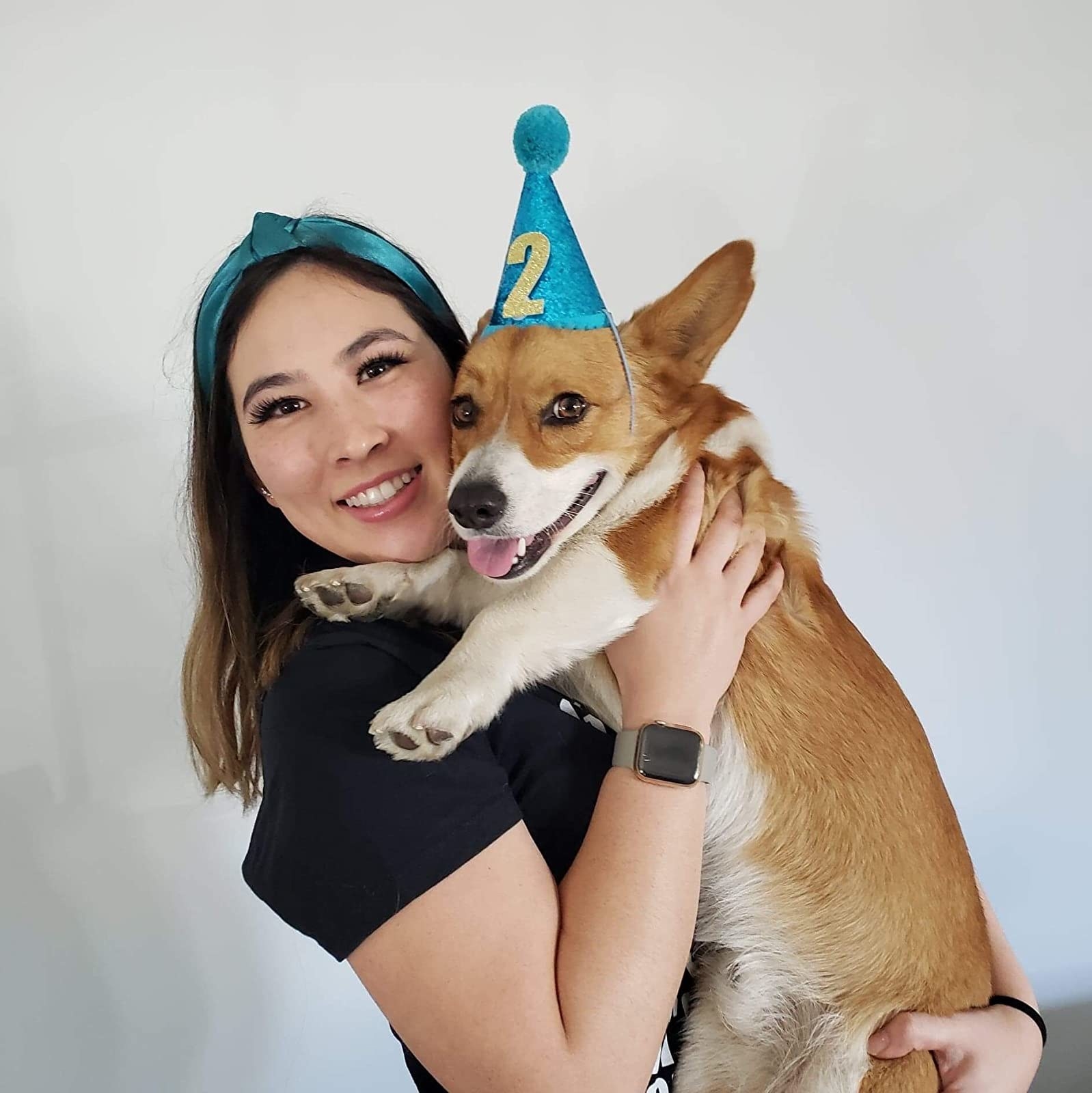 reviewer holding up dog while wearing turquoise satin headband
