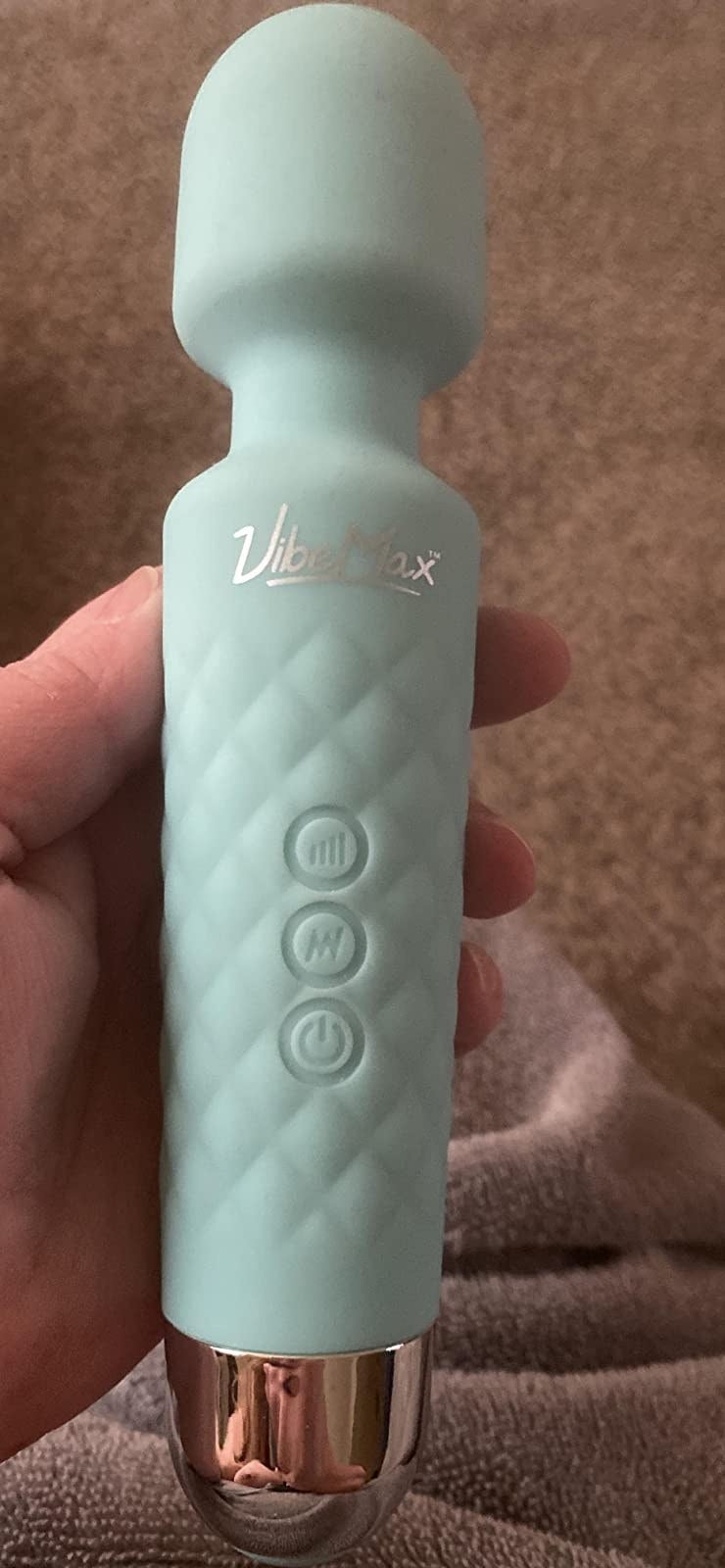A reviewer holding the wand vibrator with an enlarged round tip and a quilted shaft