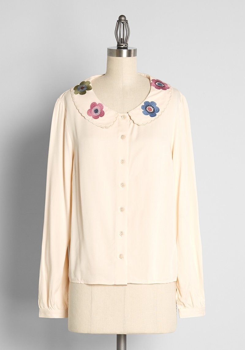 cream long sleeve top with pink blue and green flowers on the collar