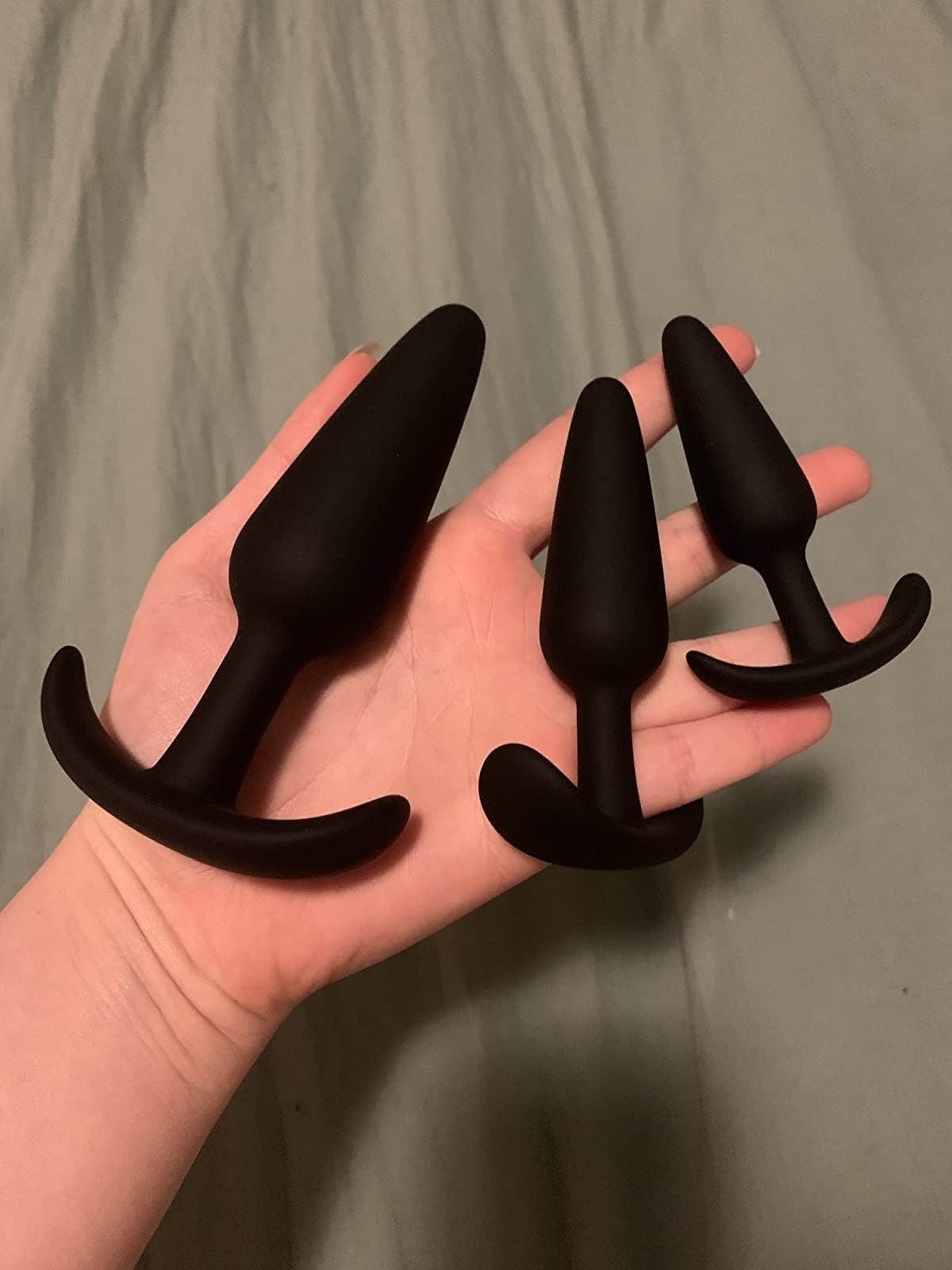 A reviewer holding the three plugs, each with a flared base