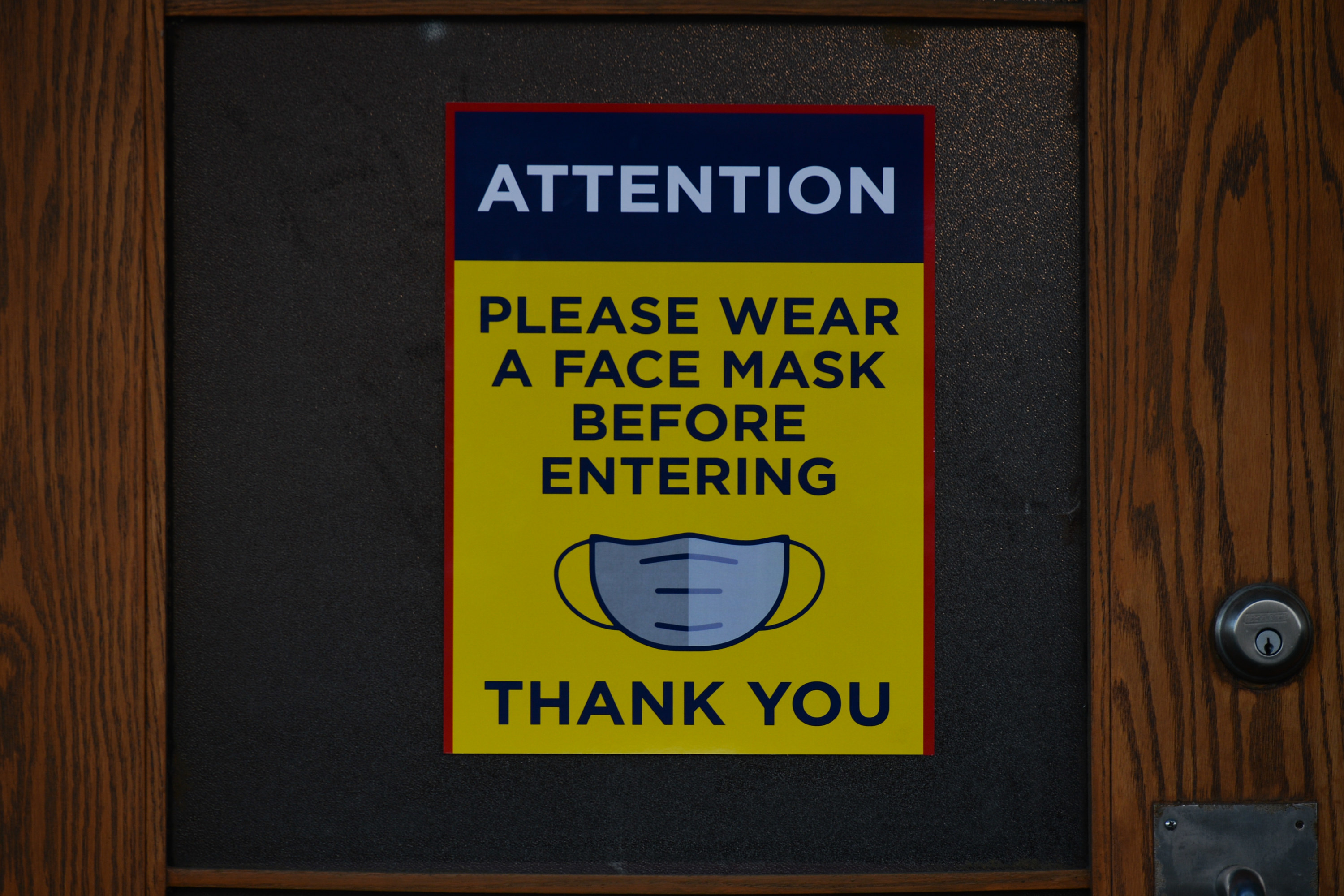Sign on door stating &quot;ATTENTION: Please wear a face mask before entering. Thank you.&quot;