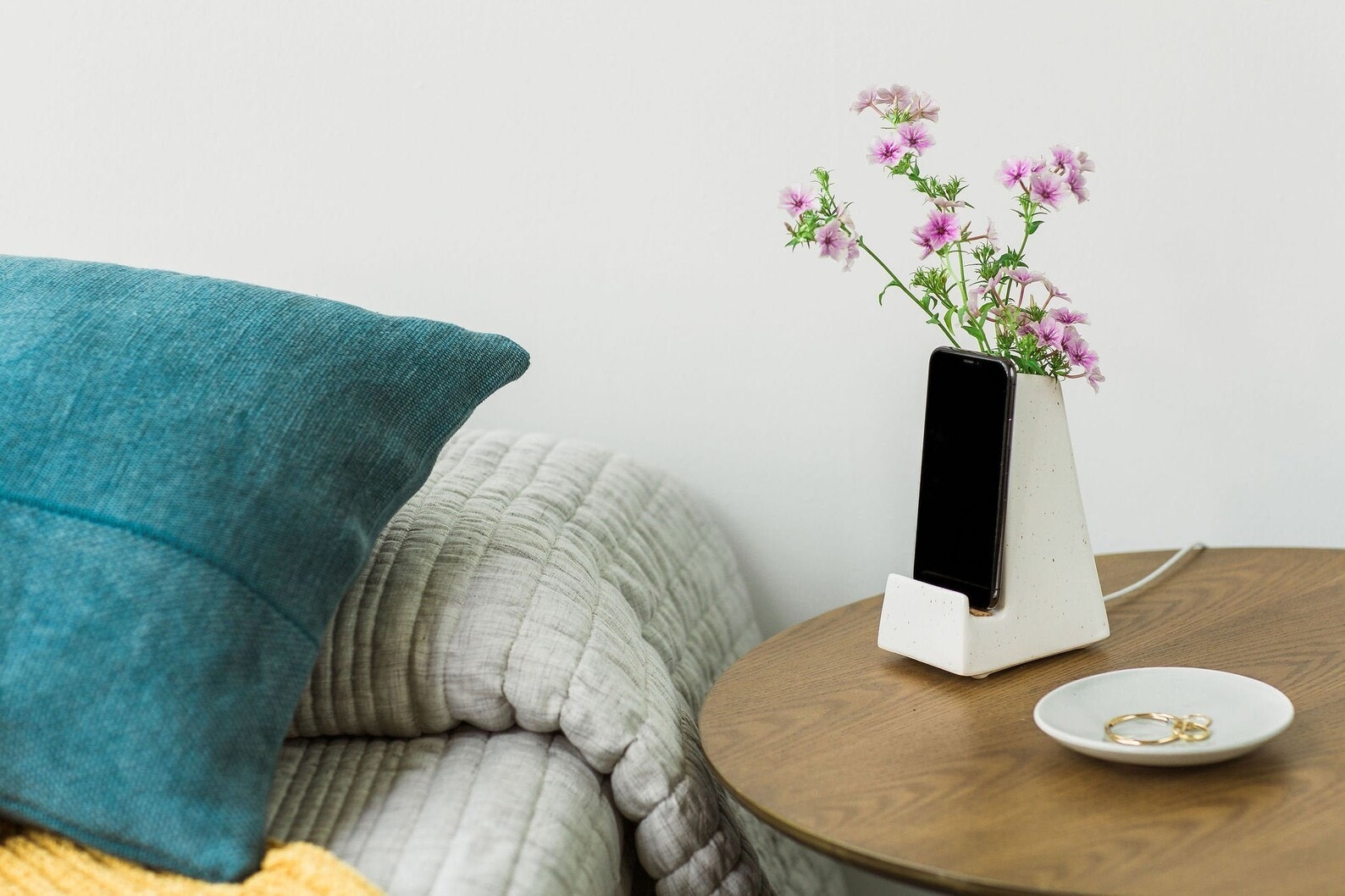 the white speckled phone dock and vase on a bedside table