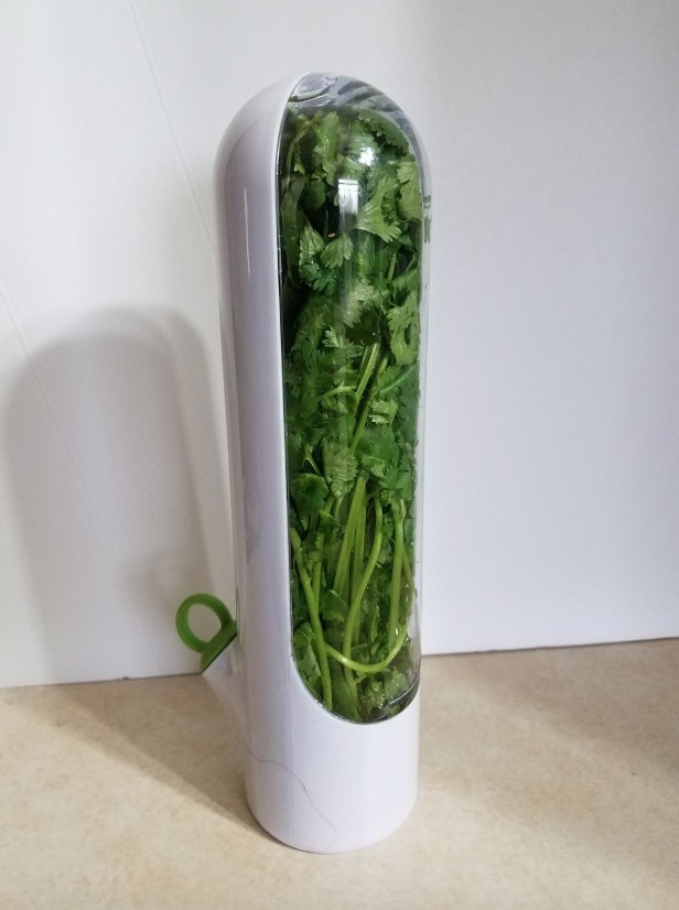 Fresh herbs in white cylindrical herb storage container