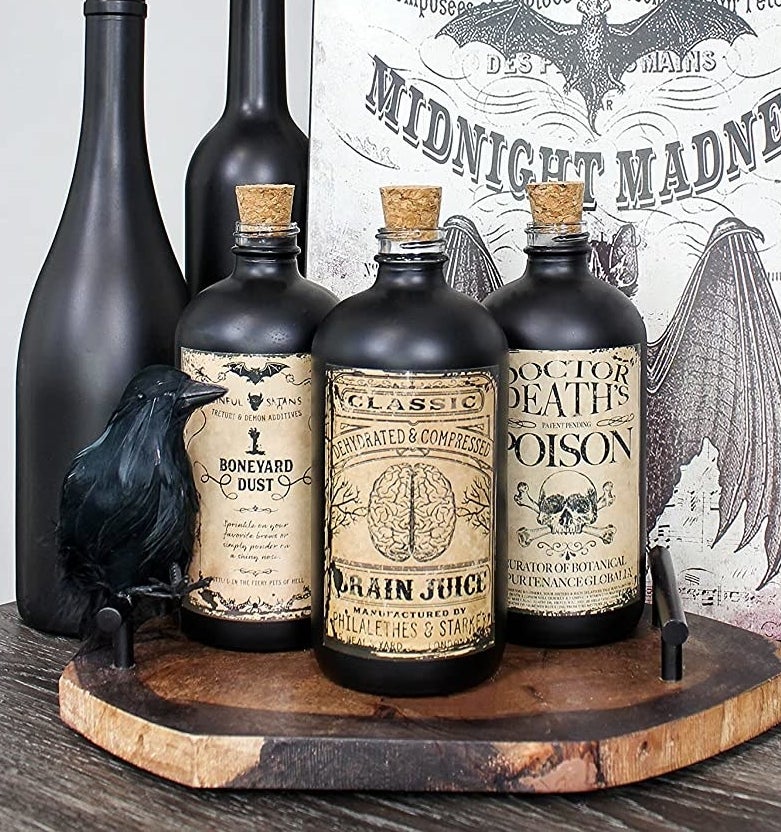 Three bottles on a wooden board next to a crow