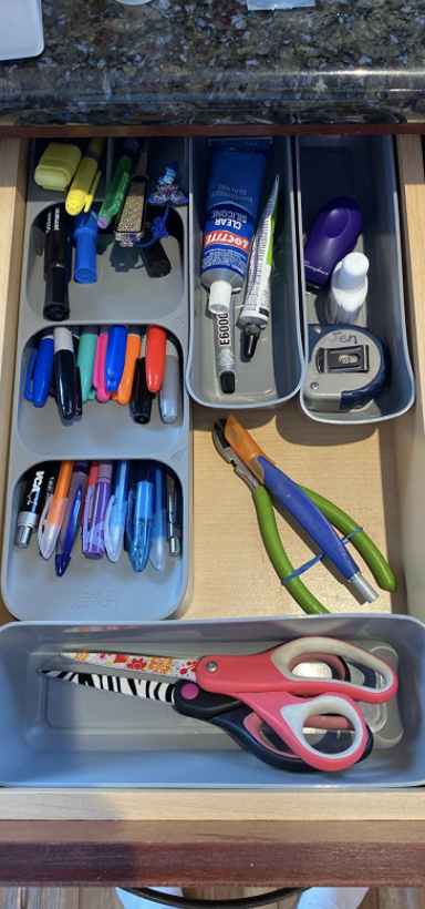 open junk drawer with pens and other various items in the slim space saving organizer
