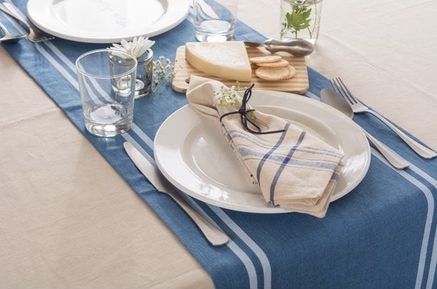 Table set with blue stripe napkins on white dinner plates.