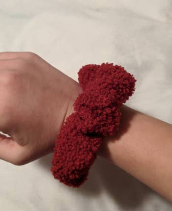 Reviewer wearing a red sherpa scrunchie on their wrist
