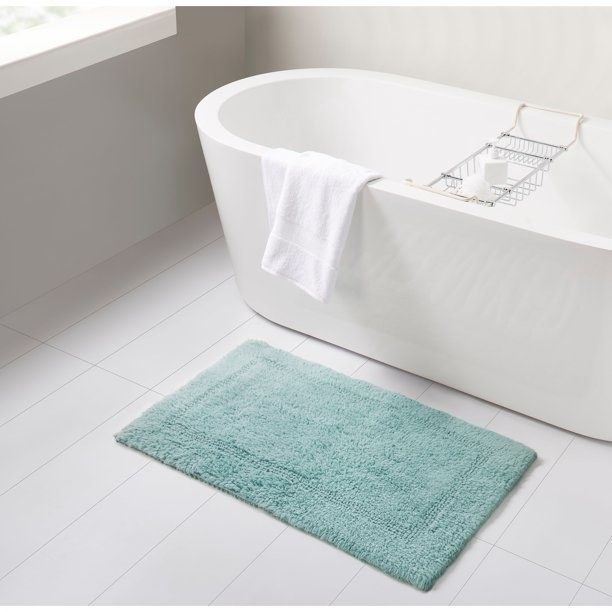 Bath mat on the ground next to a free-standing tub
