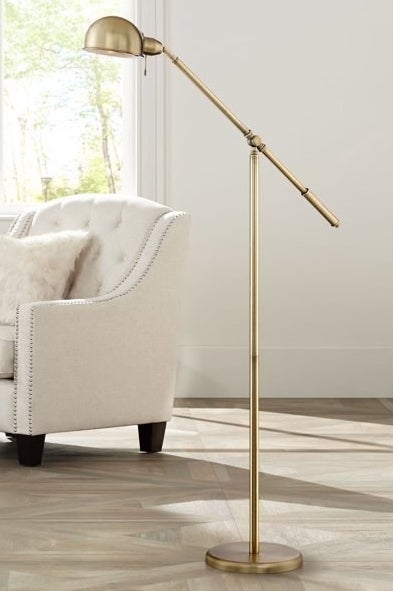 Brass floor lamp with an armchair in the background.