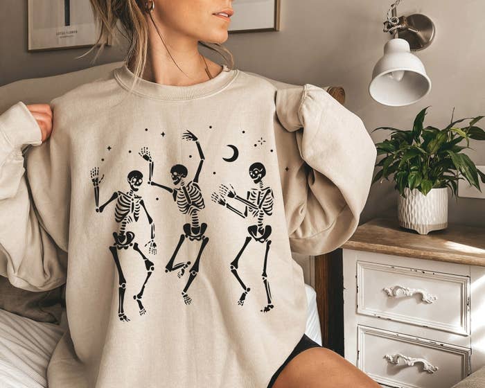 a model wearing the sand colored dancing skeletons sweatshirt