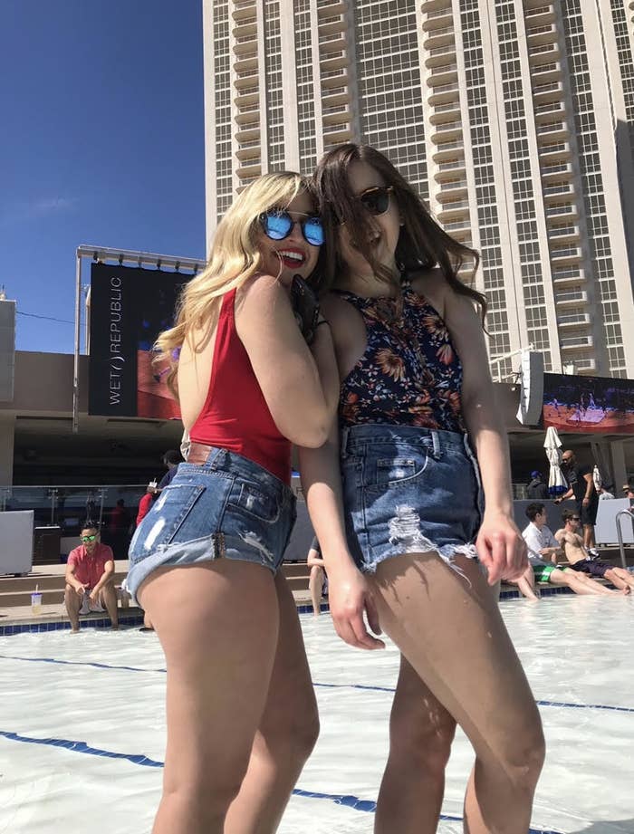 Sam posing with a friend, wearing a pair of extremely high cut denim shorts at a vegas pool party
