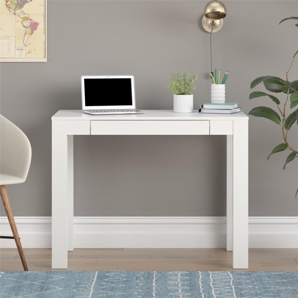 White Parsons desk with a laptop and other desk accessories on it.
