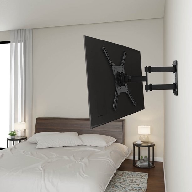TV wall mount holding TV in a bedroom, with bed and nightstands in the background.