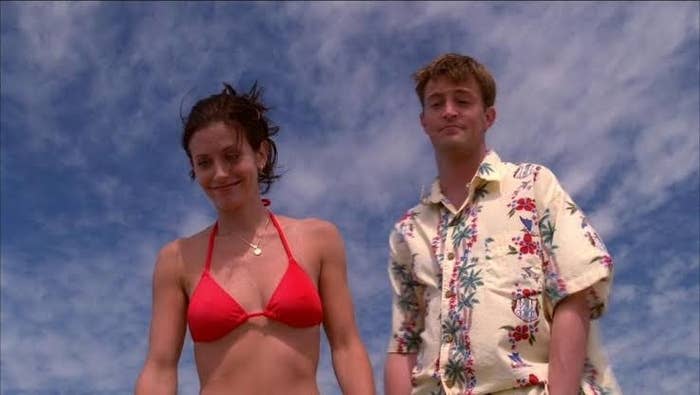 Monica and Chandler looking down at Joey on the beach