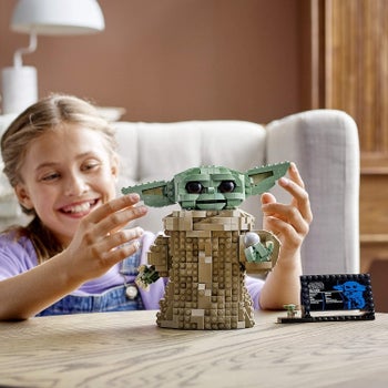 A model playing with Baby Yoda lego figure