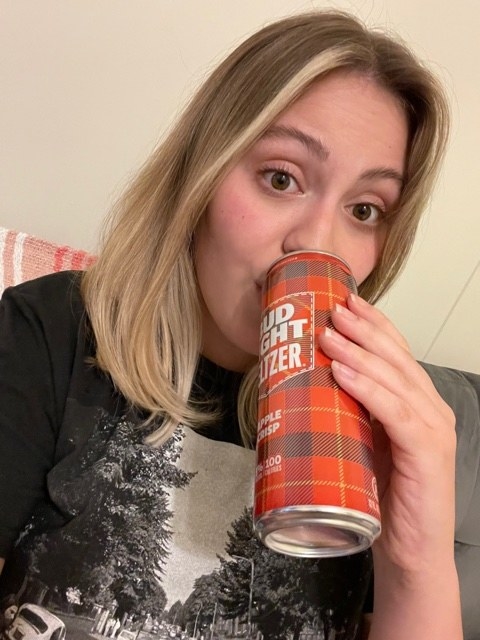 woman sipping an apple crisp seltzer from Bud Light