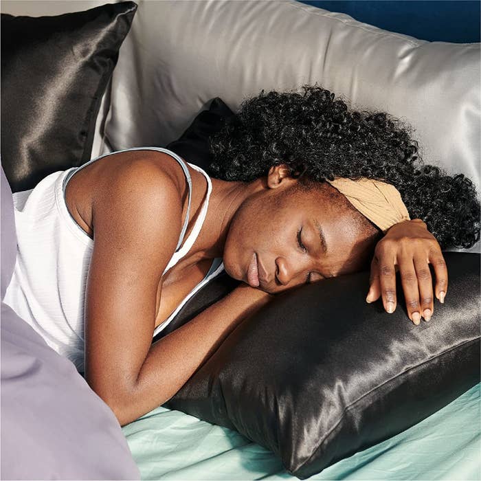 model sleeps on satin black pillow