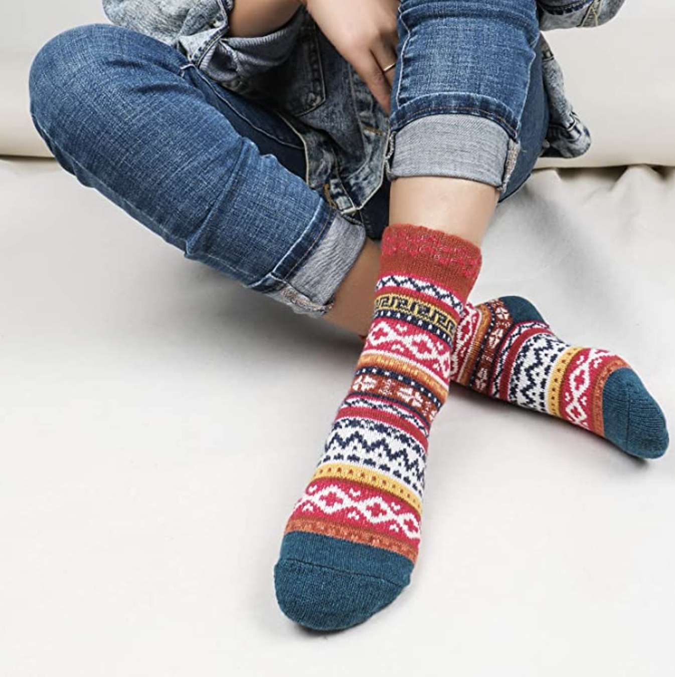 A person wearing a pair of patterned socks with jeans