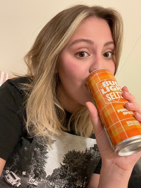 woman sipping a pumpkin spice seltzer from Bud Light