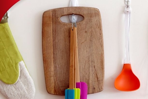 The Command hook holding a small wooden cutting board and spatulas