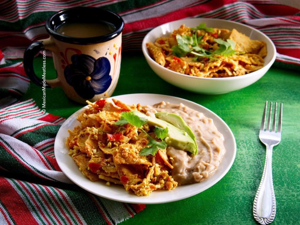 A plate with scrambled tofu and tortilla chips next to refried beans