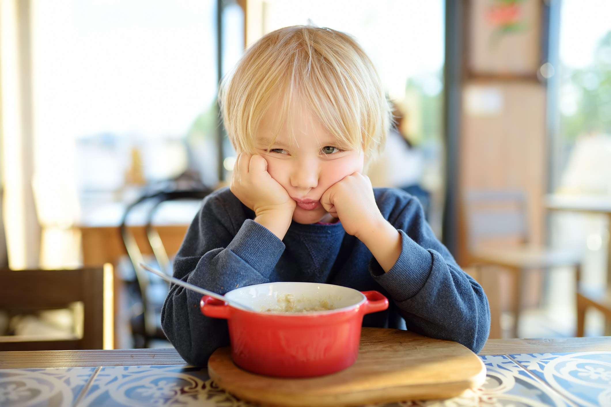 A kid sitting at the table but doesn&#x27;t want to eat