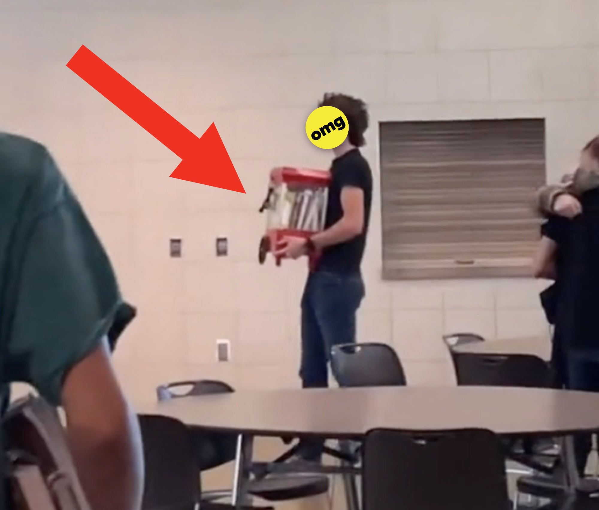 A student holding a small popcorn machine filled with notebooks