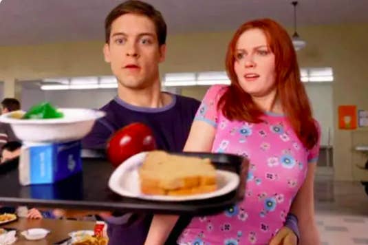Peter Parker balances a lunch tray in one hand and Mary Jane in the other