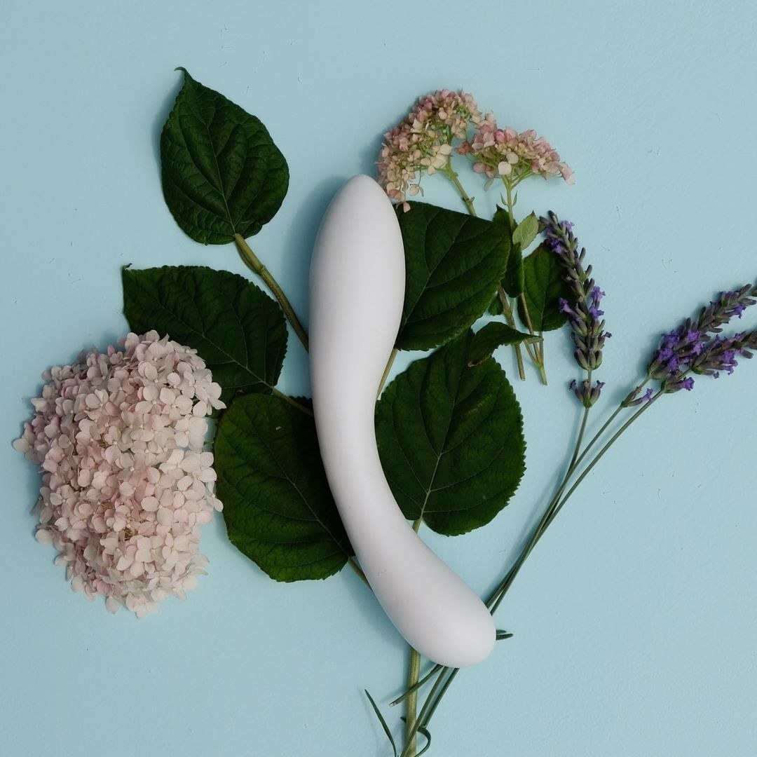 White porcelain dildo surrounded by plants