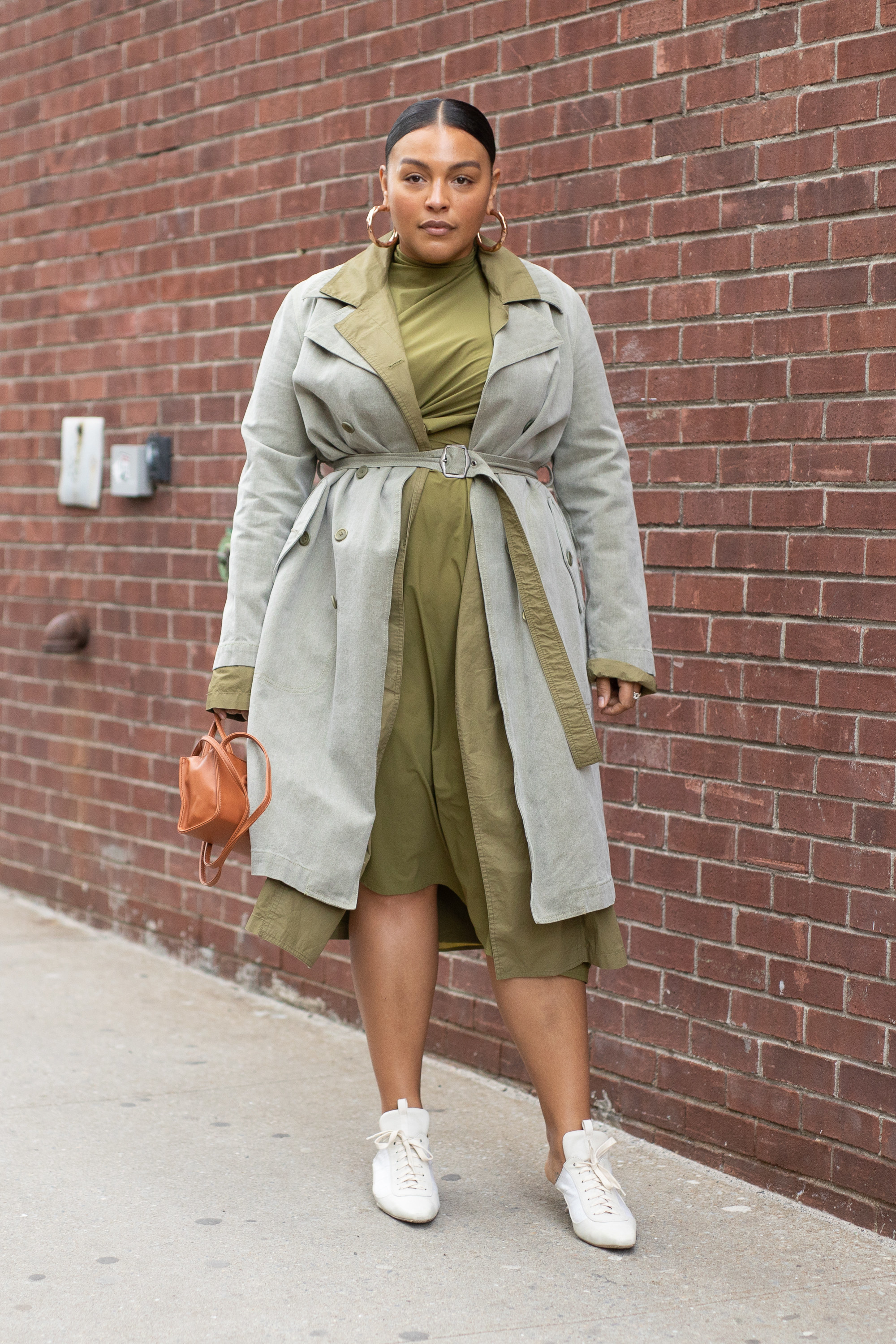 Paloma Elsesser in a green dress, grey coat, and white sneakers
